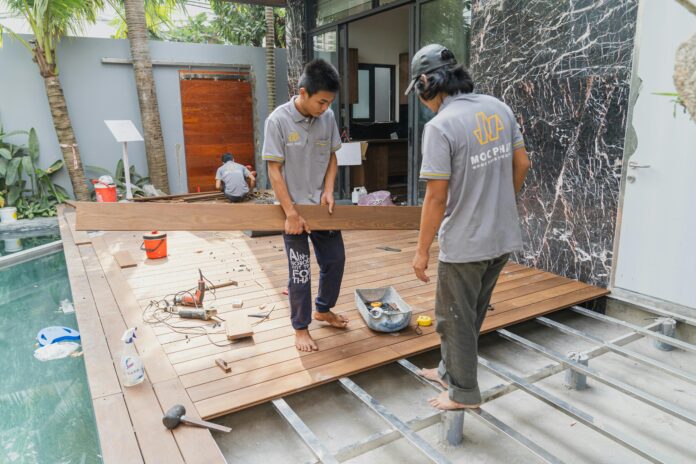 Tools and materials for DIY flooring installation, including planks, tiles, and adhesive, laid out in a home project setup. Showcases an individual installing flooring with hands-on techniques