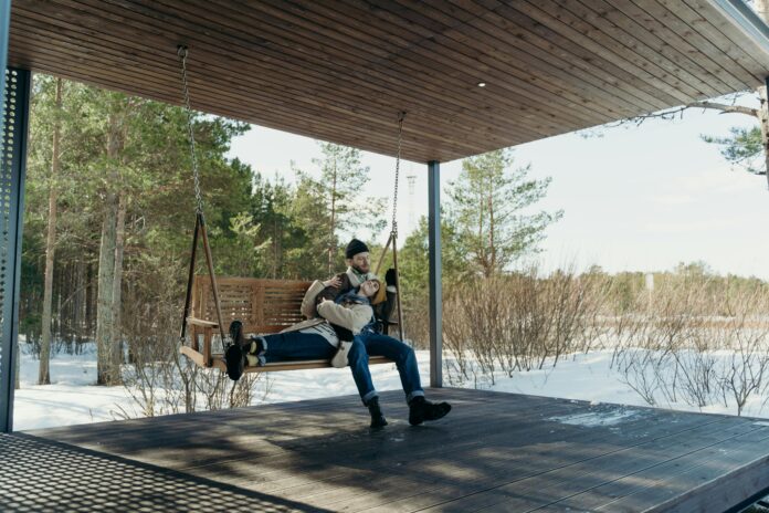 A homeowner performing seasonal deck maintenance, cleaning and inspecting wooden boards to keep the deck in top condition throughout the year.